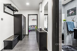 Vstupní chodba s moderní dlažbou, vestavěnými skříněmi a jednoduchým designem nabízí praktický prostor pro uložení obuvi a oblečení.