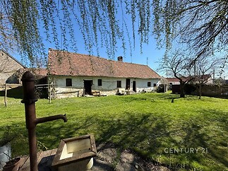 Tradiční venkovský dům s terakotovou střechou a kamennou fasádou, prostorná zahrada s udržovaným trávníkem a venkovním posezením, klidná lokalita.