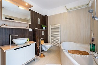 Moderní koupelna s dřevěným obkladem, velkou vanou a keramickou dlažbou, která nabízí světlý a stylový prostor.