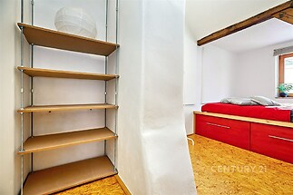 Ložnice s vestavěnými skříněmi, dřevěnou podlahou a moderním designem. Světlý interiér doplňují dřevěné trámy na stropě.