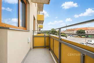 Balkon s moderní dlažbou a kovovým zábradlím, výhled na městské prostředí, ideální pro relaxaci venku.