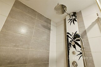 Moderní sprchový kout s keramickými dlaždicemi, designovým sprchovým panelem a stylovými vzory, ideální pro rekonstruovanou koupelnu.