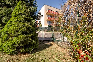 Moderní bytová budova s prostornými balkony, obklopena zelení a upravenou zahradou, nabízí klidné bydlení v atraktivní lokalitě.