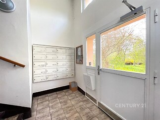 Vstupní prostor s dlažbou, poštovními schránkami a velkými okny, které propouštějí přirozené světlo, moderní a udržovaný stav.