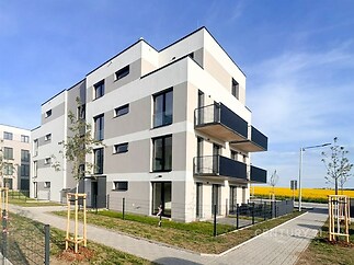 Moderní bytový dům s balkony, minimalistická architektura, kvalitní fasádní úpravy, klidná lokalita s upraveným okolím v blízkosti přírody.