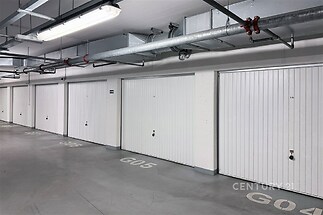 Garážové stání s bezpečnostními vraty, moderní osvětlení, betonová podlaha, vhodná pro více vozidel, čistý a udržovaný prostor