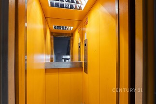 Prázdný výtah s výraznými oranžovými stěnami a kovovými doplňky, moderní osvětlení, bezpečnostní prvky, ideální pro residenční budovu.