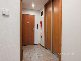 Chodba s dlažbou, vestavěné skříně s dřevěnými posuvnými dveřmi, moderní interiér a dostatek úložného prostoru