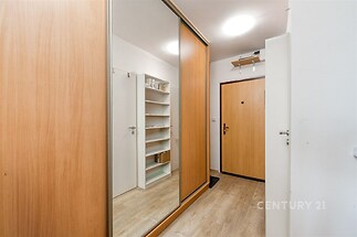 Chodba s vestavěnými skříněmi, parketová podlaha a moderní osvětlení, poskytuje praktické úložné prostory a elegantní vzhled.