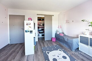 Dětský pokoj s laminátovou podlahou, vestavěným úložným prostorem a pastelovými stěnami nabízí světlý a moderní prostor k bydlení.