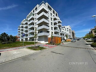 Moderní bytový dům s balkony, bílá fasáda, novostavba. Kvalitní architektura, klidná lokalita, bytové jednotky různé velikosti.