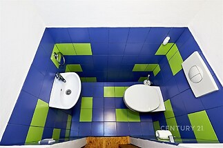 Moderní koupelna s barevnou dlažbou, modré a zelené obklady, kompaktní prostor, bílá sanitární keramika