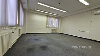 Kancelářský prostor s kobercovou podlahou, velkými okny a světlým stropem, ideální pro komerční využití, v dobrém stavu.