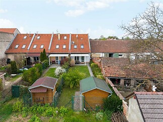 Zahrada s altánem, oplocením a přírodním trávníkem; tradiční venkovské domy s červenou střešní krytinou; klidná lokalita.