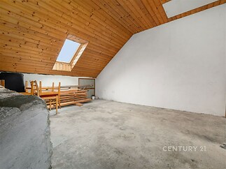Prostorná půdní místnost s dřevěným obložením a střešním oknem, betonová podlaha, vhodná k rekonstrukci nebo přeměně na obytnou část.