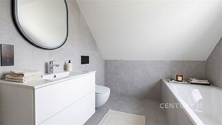 Podkrovní koupelna s moderními prvky, dlažbou a světlým designem, vybavená vanou a elegantními doplňky pro komfortní bydlení.