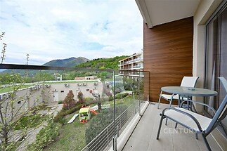 Balkon s moderní dlažbou a skleněným zábradlím, nabízí výhled na hory a okolní přírodu, ideální pro relaxaci a maximální využití plochy.