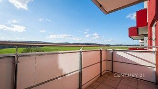 Balkón s dlážděnou podlahou nabízí panoramatický výhled na krajinu, moderní zábradlí zajišťuje bezpečnost a stylově dotváří prostor.