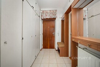 Vstupní hala s dlažbou, vestavěnými skříněmi a dřevěnými prvky, působí světlým a moderním dojmem.