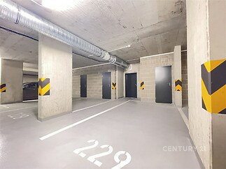 Parkovací místo v podzemní garáži s vyznačeným číslem, moderní osvětlení, betonový strop a podlaha, bezpečnostní dveře, ideální pro rezidenty.