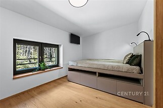 Prostorná ložnice s parketovou podlahou, vestavěnými skříněmi a velkým oknem. Moderní design zajišťuje světelnou a útulnou atmosféru.
