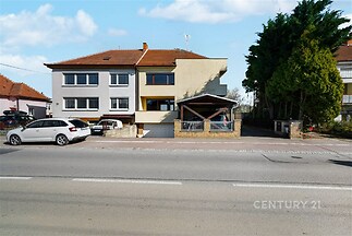 Exteriér rodinného domu s parkovacími místy, šikmou střechou a upravenou zahradou v klidné ulici. Fasáda v moderním stylu.