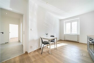 Světlá jídelna s parketovou podlahou, velkými okny a moderním vybavením, nabízí útulný a rekonstruovaný prostor pro stolování.