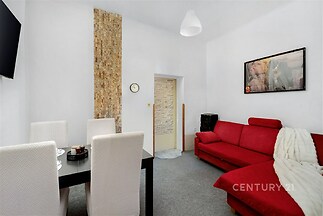 Světlý obývací pokoj s moderním nádechem, červená sedačka a konferenční stůl, textilní koberec a dekorativní kamenný obklad na stěně