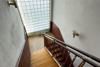 Dřevěné schodiště s parketovou podlahou a moderními skleněnými tvárnicemi, které poskytují dostatek světla.