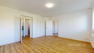 Světlý obývací pokoj s parketovou podlahou a bílými stěnami nabízí moderní design a prostorný interiér, ideální pro rodinné bydlení.
