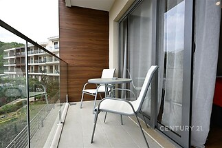 Balkon s moderními skleněnými zábradlími, dlažbou a výhledem do zeleně, ideální pro relaxaci a venkovní posezení.