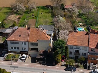 Řadový dům s červenou střechou, prostorná zahrada, parkování před domem, klidná lokalita v blízkosti přírody.