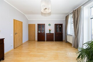 Prostorný obývací pokoj s parketovou podlahou, velká okna zajišťují světlost místnosti, moderní vestavěný nábytek dotváří elegantní styl.