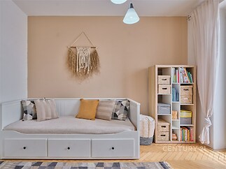 Pokoj pro hosty s parketovou podlahou, světlý interiér a knihovna.