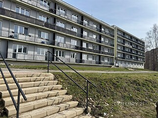 Bytový dům s moderní fasádou, balkony a plastovými okny poblíž zeleně, vhodný pro rodinné bydlení v klidné lokalitě.