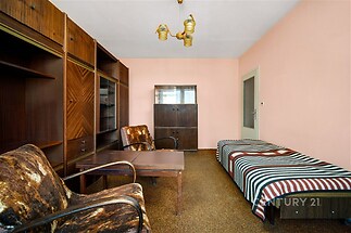 Útulný obývací pokoj s dřevěným nábytkem, koberci na podlaze a vintage osvětlením, ideální pro milovníky retro stylu.