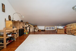 Podkrovní úložný prostor s parketovou podlahou a dřevěným nábytkem, ideální pro skladování, světlý interiér s moderními prvky.