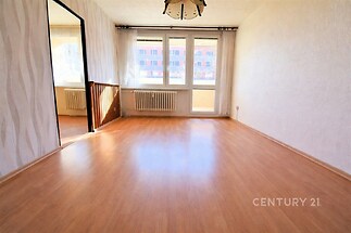 Světlý obývací pokoj s parketovou podlahou a velkými okny, moderní design, čerstvě rekonstruovaný, ideální prosluněný prostor pro bydlení.