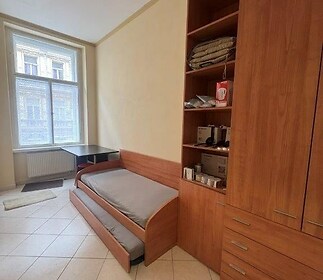 Pokoj s dlažbou, vestavěnými skříněmi a velkými okny poskytuje světlý interiér v moderním stylu.