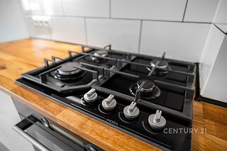 Moderní kuchyň s plynovým sporákem, dřevěnou pracovní deskou a bílými obklady, elegantní provedení vytváří přívětivý dojem a nadčasový styl.