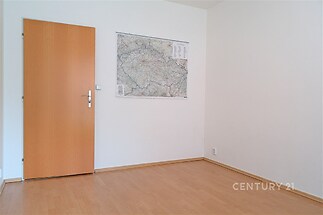 Prázdný pokoj s parketovou podlahou, bílými stěnami a dřevěnými dveřmi, ideální pro personalizaci a moderní úpravy.