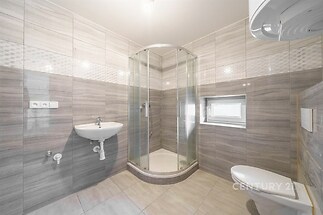 Moderní koupelna s velkoformátovými dlaždicemi, sprchovým koutem a závěsnou toaletou, která nabízí světlé a účelné uspořádání.