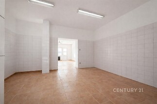 Světlá kuchyň s dlažbou, bílými obklady a velkými okny, moderní úprava, prostorný interiér vhodný k úpravám podle vlastního stylu