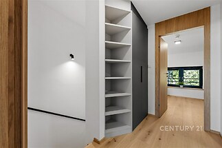 Světlá chodba s dřevěnou podlahou a vestavěnými policemi nabízí moderní design a praktické úložné prostory.