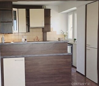 Moderní kuchyň s parketovou podlahou, vestavěné skříně, světlý prostor díky velkým oknům.