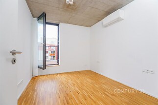 Prázdná ložnice s parketovou podlahou, velkými okny a moderní klimatizací nabízí světlý prostor ideální pro osobní přizpůsobení.