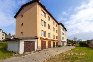 Čtyřpodlažní bytový dům s garážemi, nová fasáda, velká okna, nachází se na klidném místě s dostatkem zeleně a parkováním.