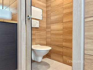 Moderní koupelna s dřevěným obkladem, světlá dlažba a závěsné WC zajišťují stylový a čistý designový prostor.
