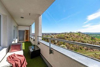 Prostorný balkon, umělý trávník, výhled na krajinu, moderní zábradlí, světlé otevřené prostory.