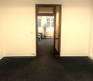 Průchod do světlé kanceláře s tmavým kobercem a velkými okny, moderní topný systém, minimalistický design.
